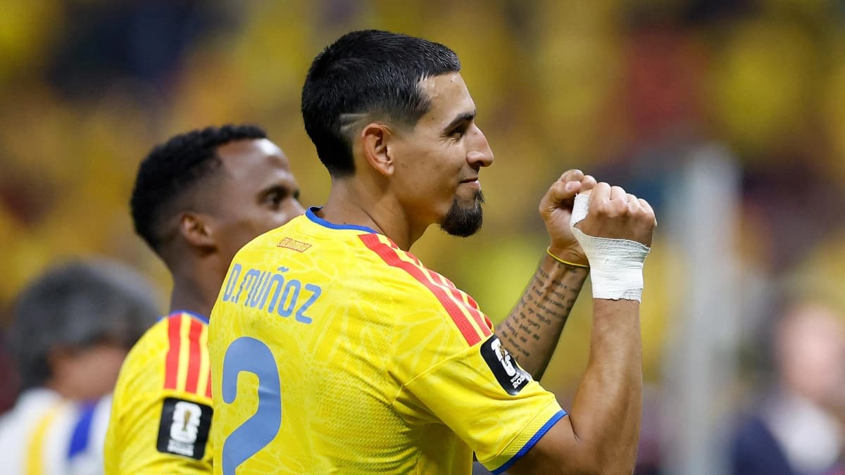 Daniel Muñoz, de espaldas con la camiseta amarilla número 2 de la Selección Colombia y una venda en la mano derecha, aprieta los puños durante un partido
