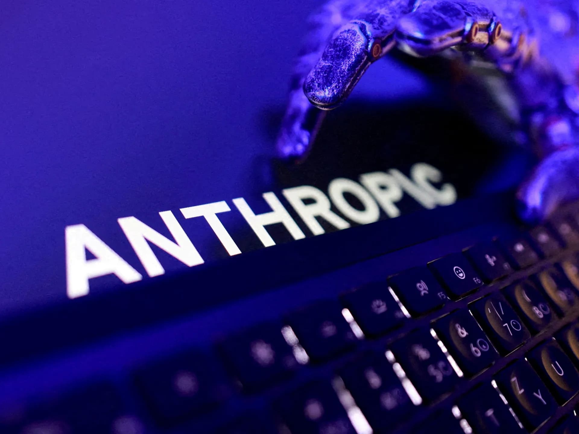 El nombre Anthropic en la pantalla de un computador portátil junto a un teclado, con iluminación azul
