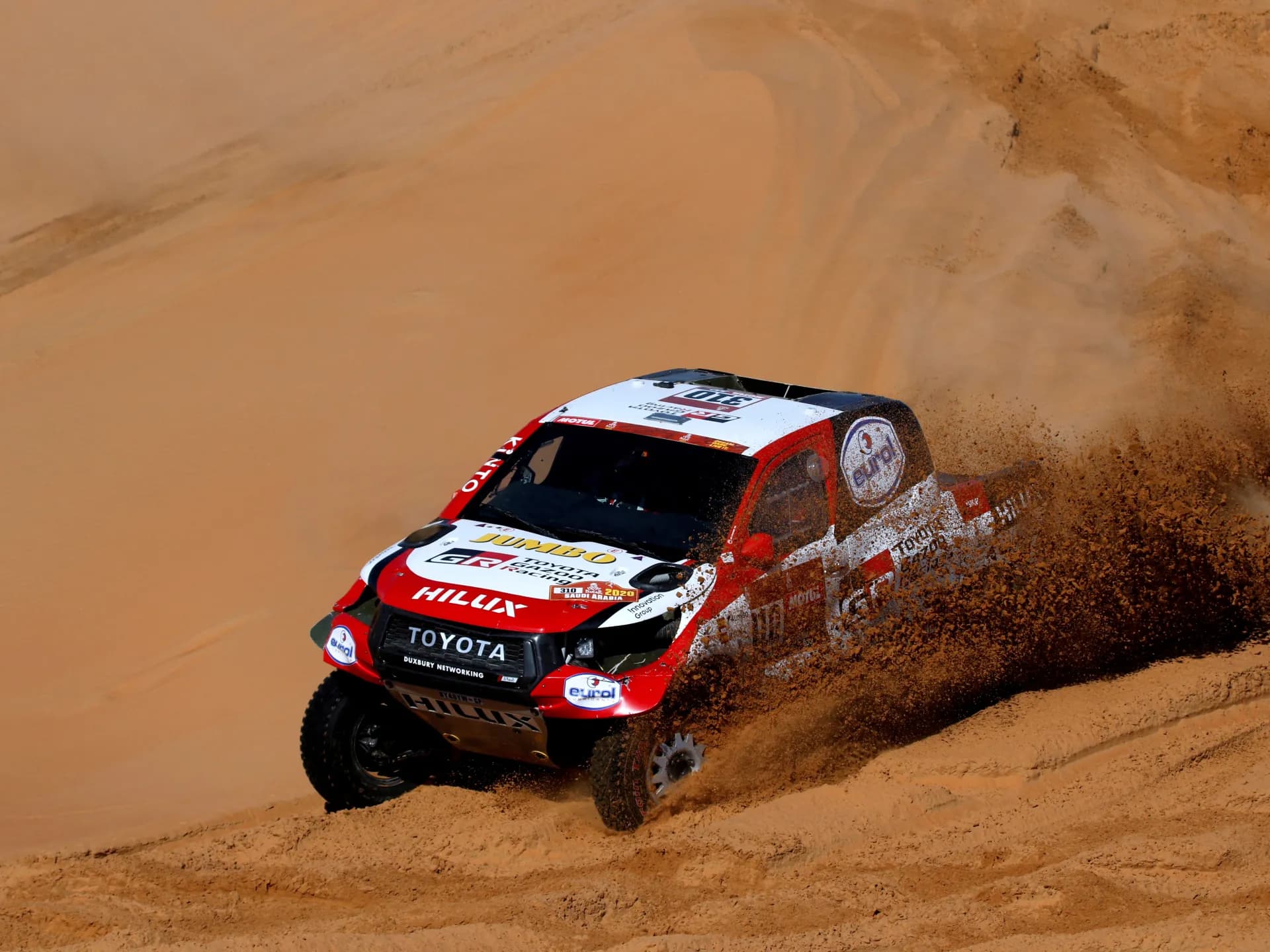 Una camioneta Toyota Hilux de competencia levanta arena al bajar una duna durante una edición del Rally Dakar en Arabia Saudí