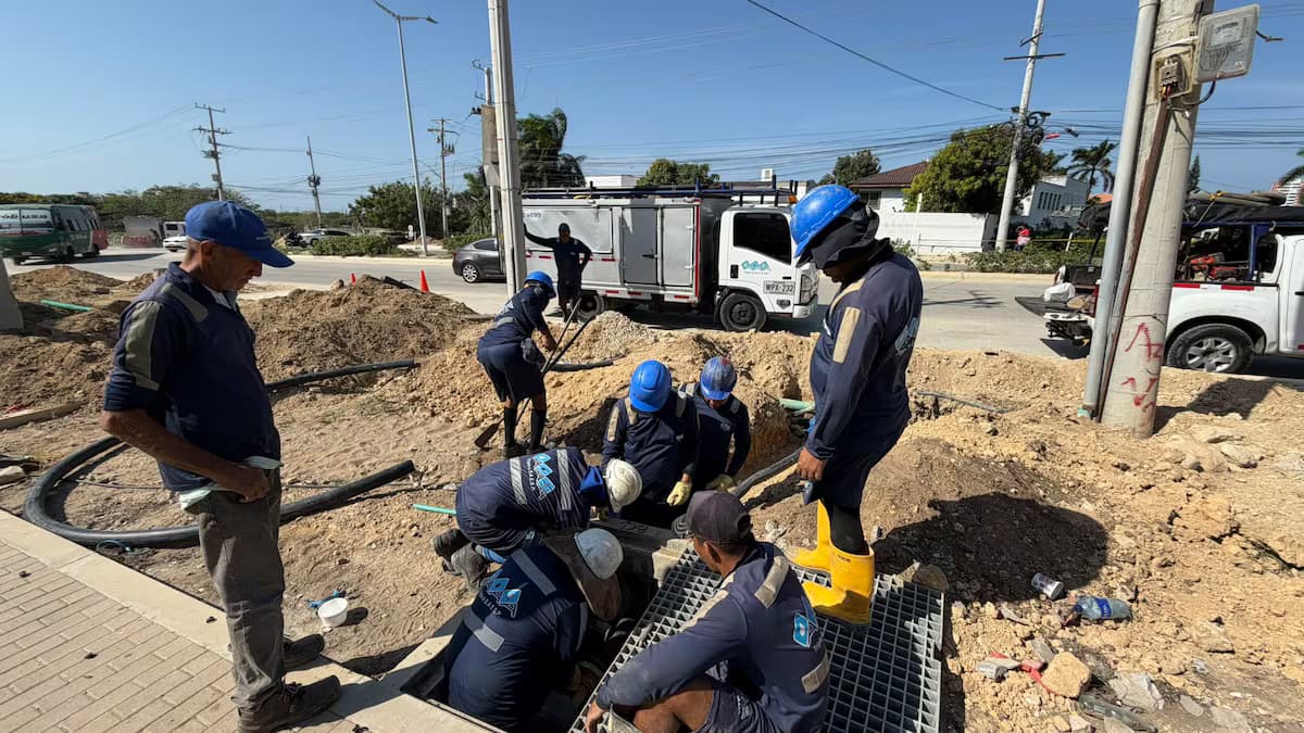 Operarios de acueducto con cascos azules trabajan dentro de una zanja abierta en una vía de Barranquilla