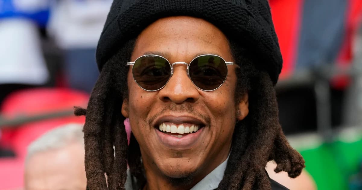 El rapero Jay-Z sonríe con gafas oscuras y gorro negro