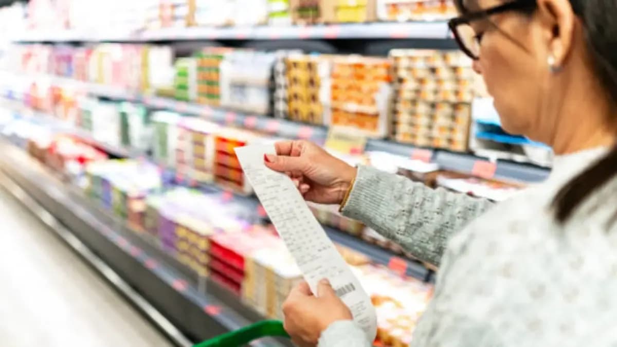 Una mujer revisa el recibo de compra frente a una góndola de supermercado