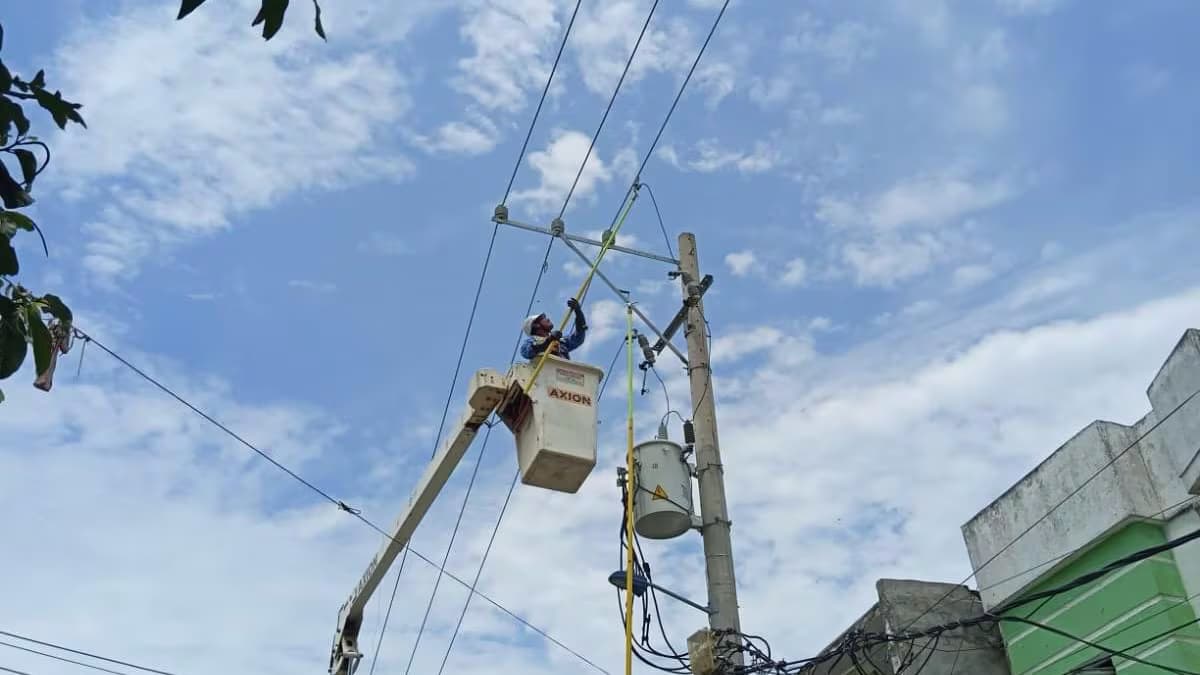 Un operario trabaja desde una canasta elevada en una red eléctrica de la región Caribe