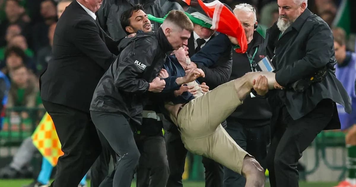 Personal de seguridad retira de la cancha a un hombre que portaba una bandera palestina durante el partido entre Irlanda y Austria en Dublín