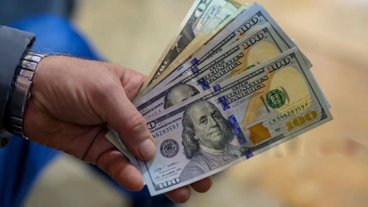 Una persona sostiene varios billetes de 100 dólares