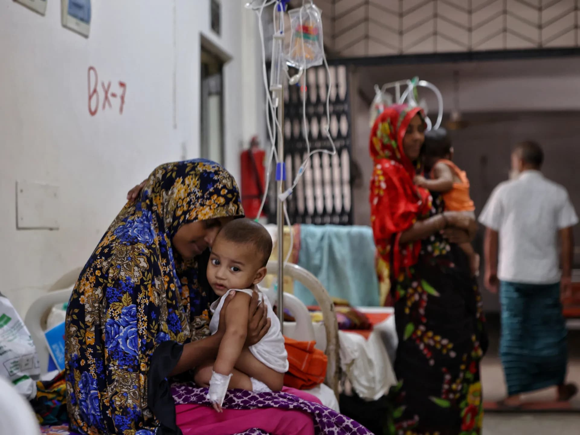 Una madre sostiene a su hijo de nueve meses, enfermo de sarampión, en el Hospital de Enfermedades Infecciosas de Daca