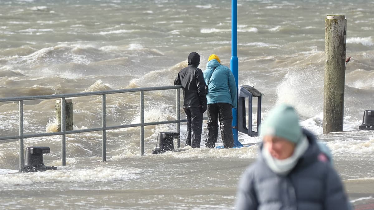 Dos personas observan el oleaje que inunda un muelle durante el temporal en el norte de Europa