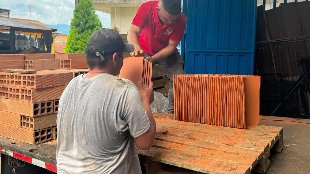 Dos hombres descargan tejas de barro y ladrillos de un camión en un municipio del Suroeste antioqueño