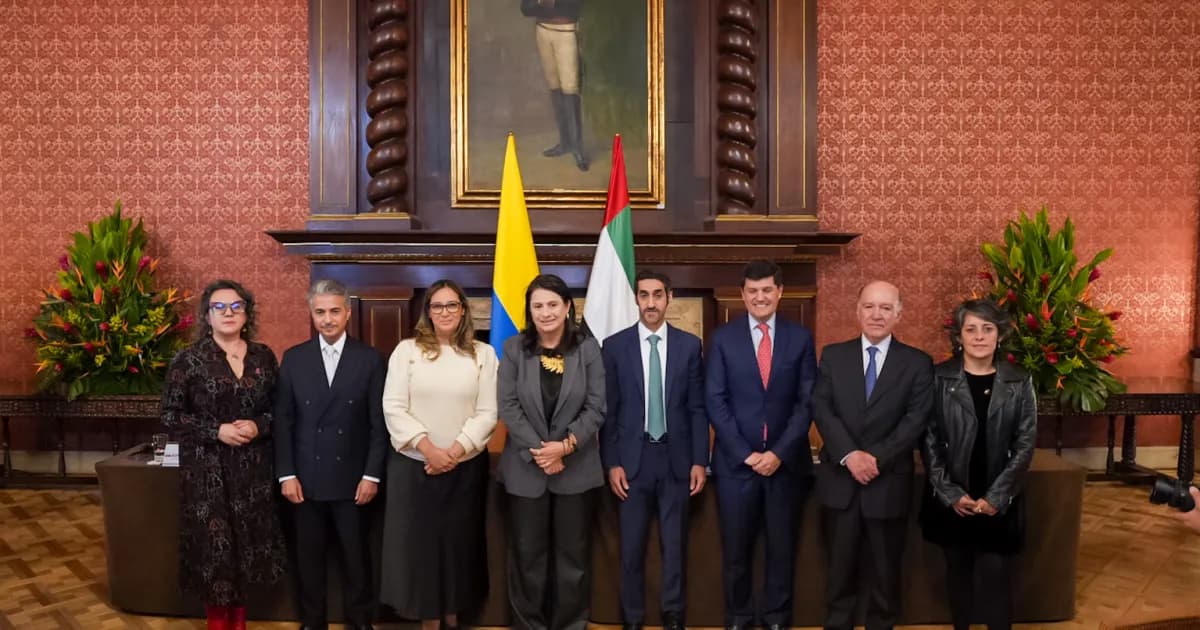 Delegaciones de Colombia y de Sharjah posan frente a las banderas de ambos países en el Palacio de San Carlos, en Bogotá