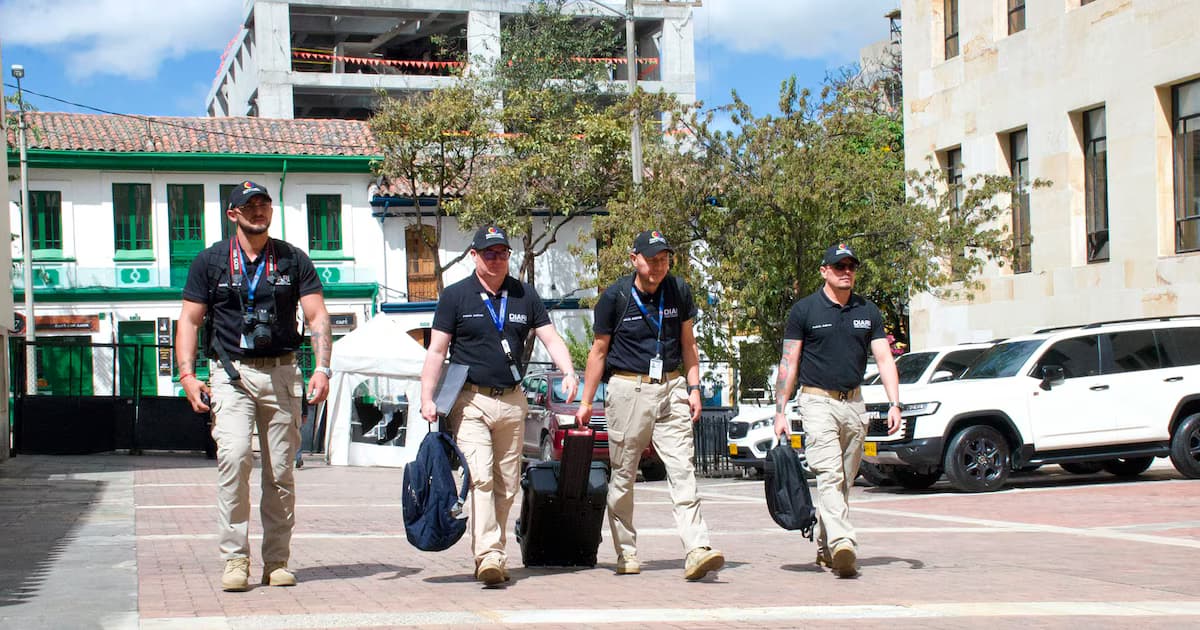 Cuatro investigadores con chalecos y maletines caminan hacia la sede del Ministerio de Hacienda en Bogotá