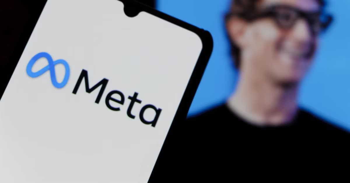 Un teléfono móvil muestra el logotipo de Meta sobre fondo blanco, con una pantalla desenfocada detrás