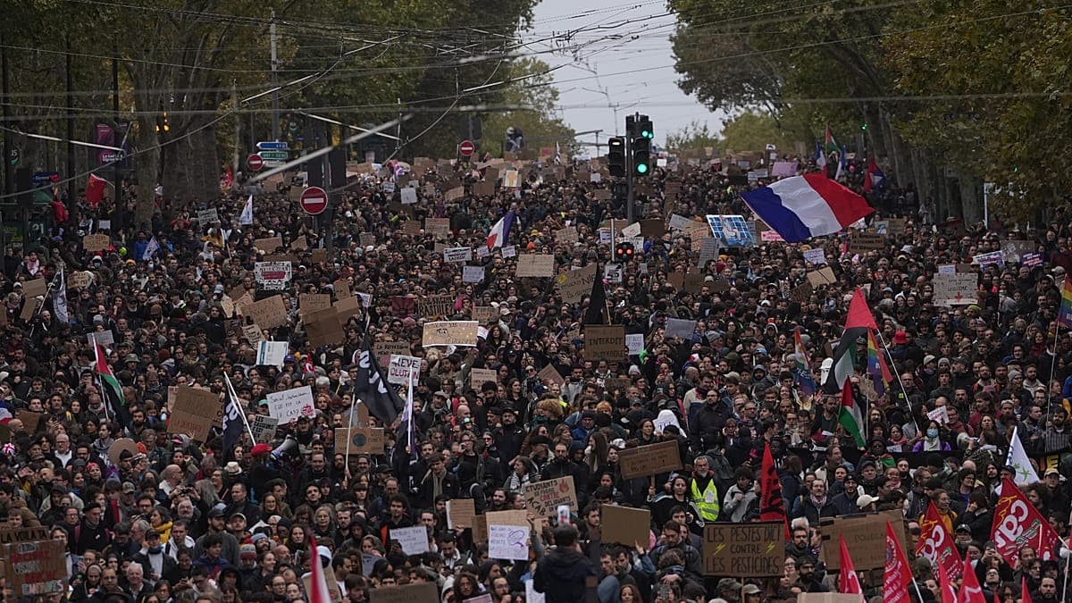 Miles de manifestantes marchan con pancartas y banderas por una avenida de París